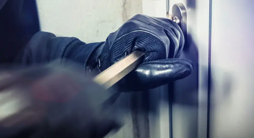 Main gantée utilise un pied-de-biche pour forcer une porte. L'effraction porte ses fruits.