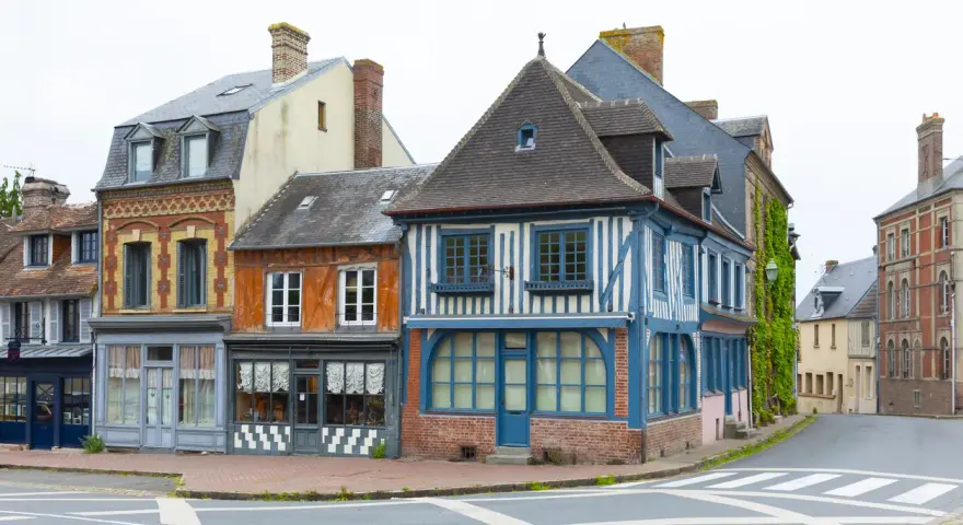 Façades colorées de maisons anciennes, dont une à colombages bleus et blancs. Une description d'une fenêtre ancienne orne la façade orange.