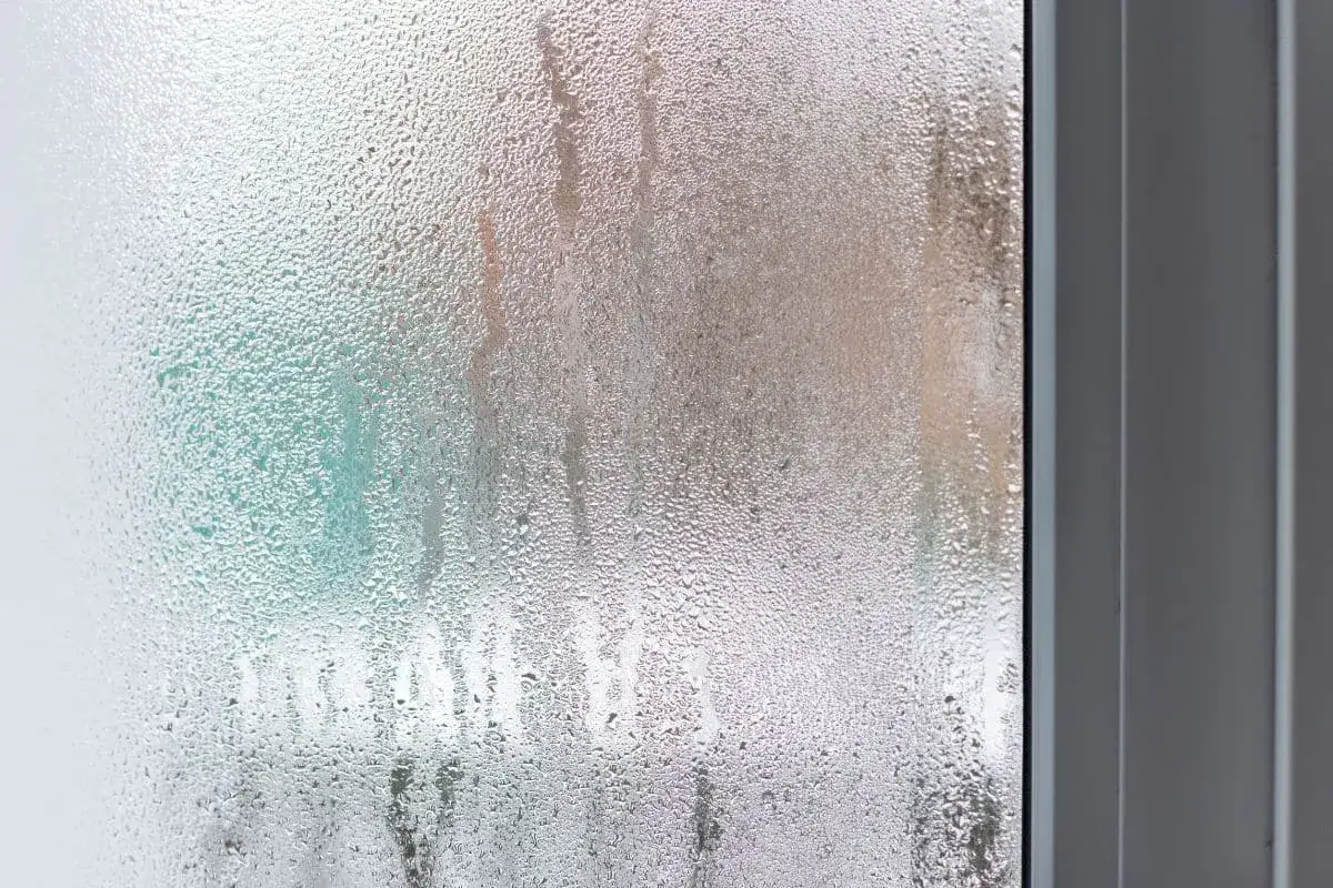 Gouttes de condensation sur une fenêtre, suggérant une isolation thermique médiocre et un coefficient Uf élevé.