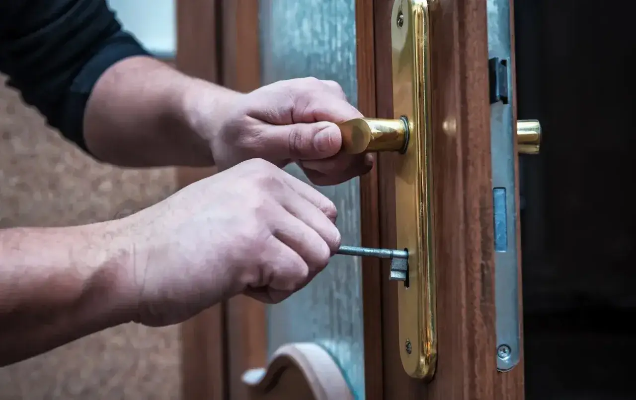 Mains insérant une clé dans une serrure, la poignée de porte qui grince annonce l'ouverture.