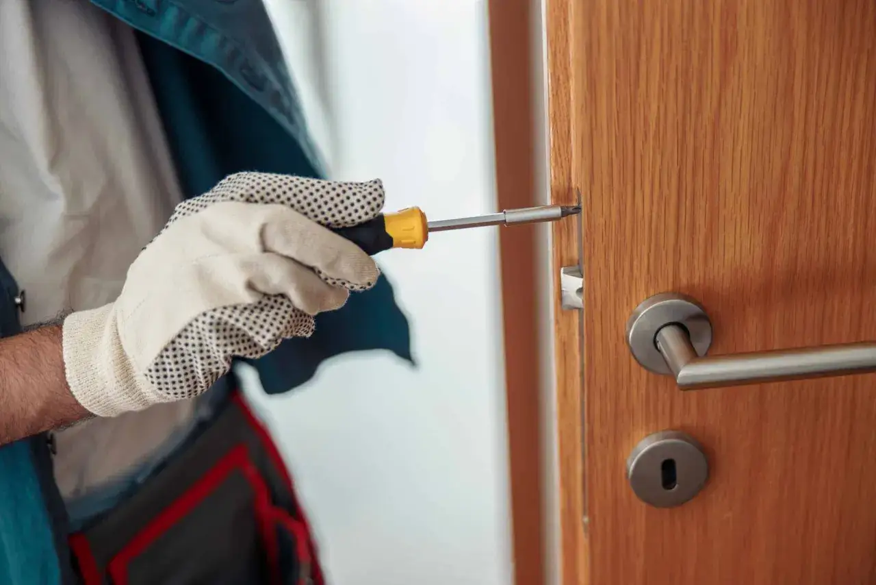 Un bricoleur utilise un tournevis pour ajuster la serrure d'une porte en bois, une &eacute;tape cl&eacute; pour savoir comment ouvrir une porte ferm&eacute;e.