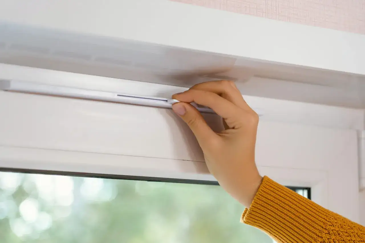 Main tenant ajuste le syst&egrave;me de ventilation de la fen&ecirc;tre pour nettoyer l'air.