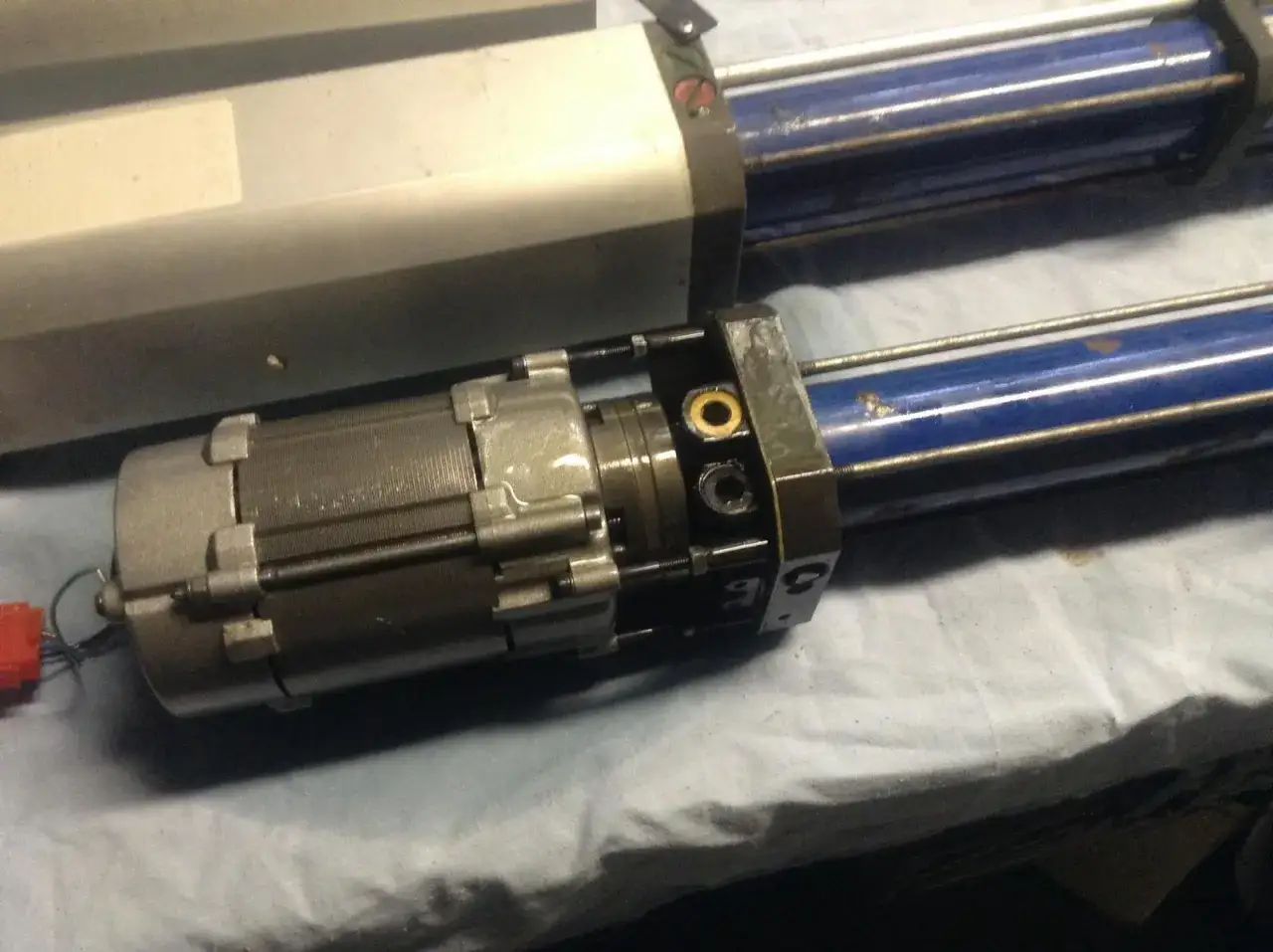V&eacute;rins de portail avec moteur. Quelle huile pour v&eacute;rin de portail ? L'image montre des v&eacute;rins hydrauliques bleus et un moteur gris.