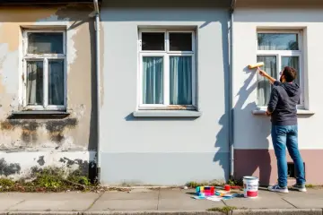 Un homme peint une fenêtre extérieure. Des pots de peinture et des nuanciers sont posés sur le trottoir, prêts pour la décoration de fenêtre extérieur.