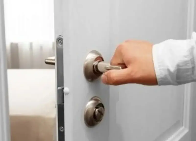 Main tenant essaie d'ouvrir une porte, mais la poignée de porte impossible à enlever bloque l'accès.