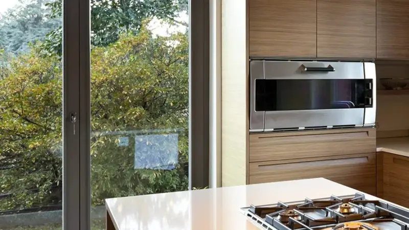 Cuisine moderne avec une grande fenêtre offrant une vue sur la nature. L'isolation phonique de la fenêtre assure un affaiblissement acoustique, créant un havre de paix.